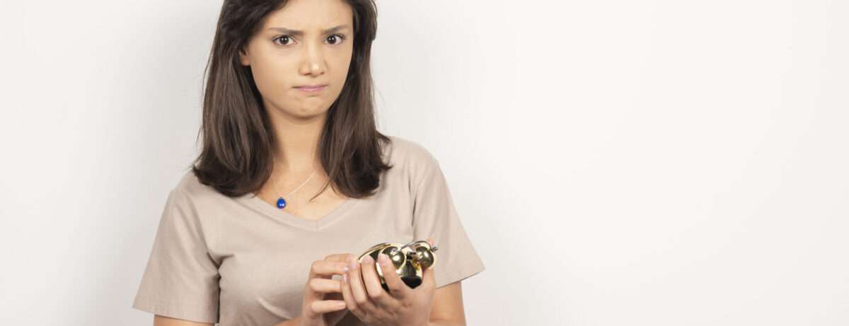Young woman holding alarm clock on white background . High quality photo